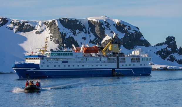 Small ship in Antarctica with a skiff full of guests leaving. 