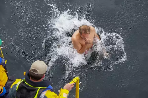 Man jumping into the water in Antarctica from his small ship during  a polar plunge event. 