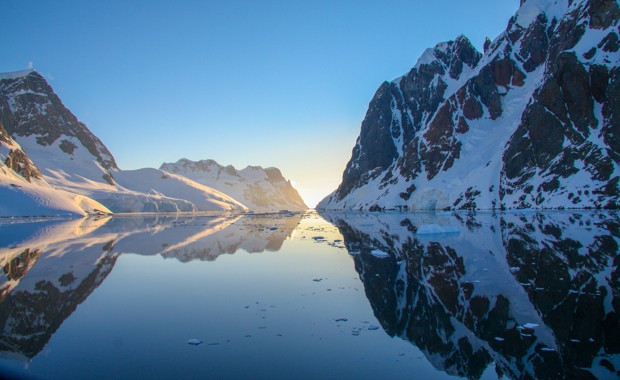 Reflection of mountains in a calm channel seen from a small ship cruise in Antarctica. 