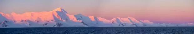 Sunset turning the mountains pink in Antarctica seen from a small ship cruise. 