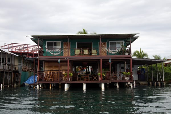 View of Bocas Inn from the water with rooms facing the ocean and open air restaurant and hammocks.