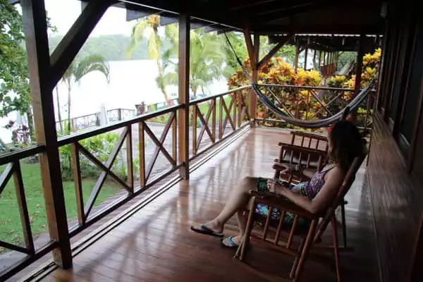 Traveler in Costa Rica rocking on a chair on the deck overlooking the river and garden.