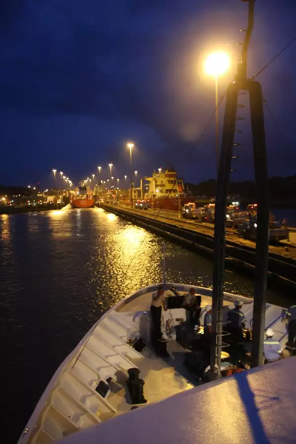 Bow of a small ship cruise going through locks in the Panama canal in the evening. 