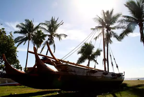 Hawaiian double-hulled canoe pulled up onto the beach