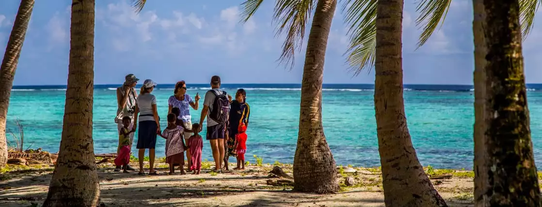 Guests from a small cruise ship talking with locals on the beach in the south pacific islands. 
