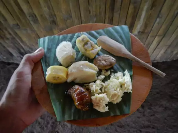 Plate of seafood and bananas on a banana leaf with wooden spoon.