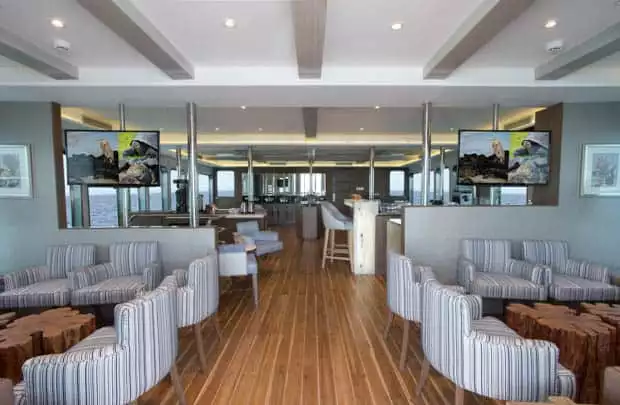 Interior view of the sitting area with 2 television screens, bar and dining area.