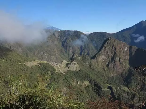 Landscape view of Peruvian mountain ranges with Machu Pichu on the mountainside in the distance.