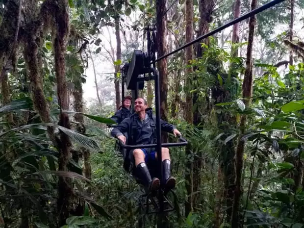 Happy travelers on a open air gondola gliding through the rainforest.