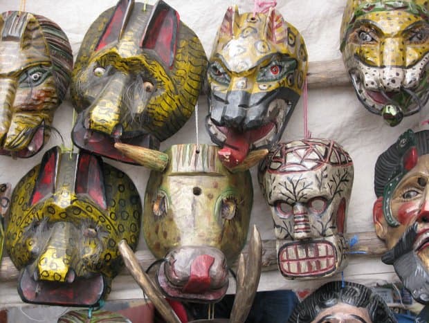 Colorful Mayan mask reproductions of animals, skeleton and male heads.
