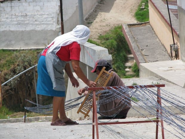 2 local women weaving textiles.