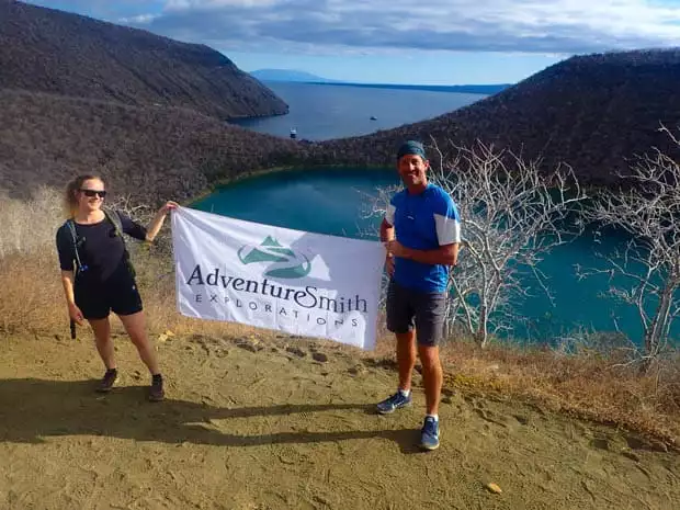 Galapagos travelers holding the Adventuresmith Explorations flag on the bluff overlooking Sullivan bay.