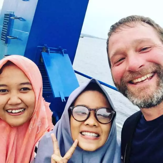 Happy guest aboard the small ship Ombak Putih smiling with two Indonesia women.  
