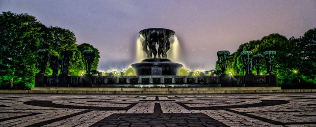 A large fountain in a courtyard illuminated at night