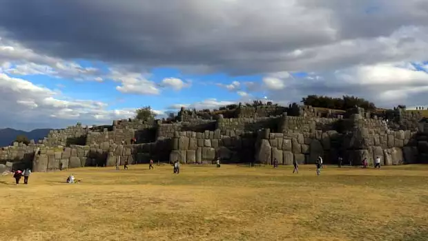 View of a Inca stone ruin with tourists walking about on a Peruvian land tour.