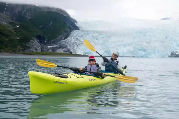 A mom and son kayaking near a glacier in Alaska. 