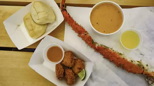 A meal of Alaskan king crab, soup and fried fish on a table.