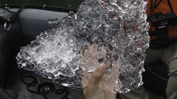 Alaskan small ship crew members hand holding a piece of a ice berg in a zodiac.