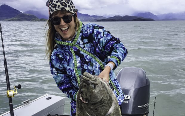 An Alaskan traveler holding a king salmon on a boat in the ocean.