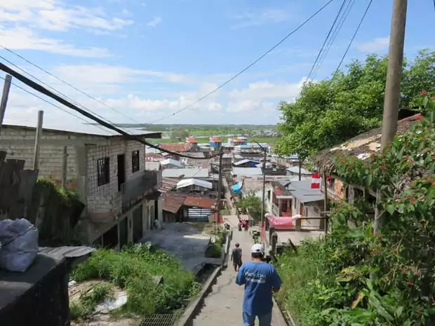 People walking down a stairway with old worn down buildings and houses an either side. 
