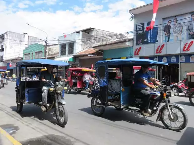 A busy street filled with mototaxi's driving by in Peru. 