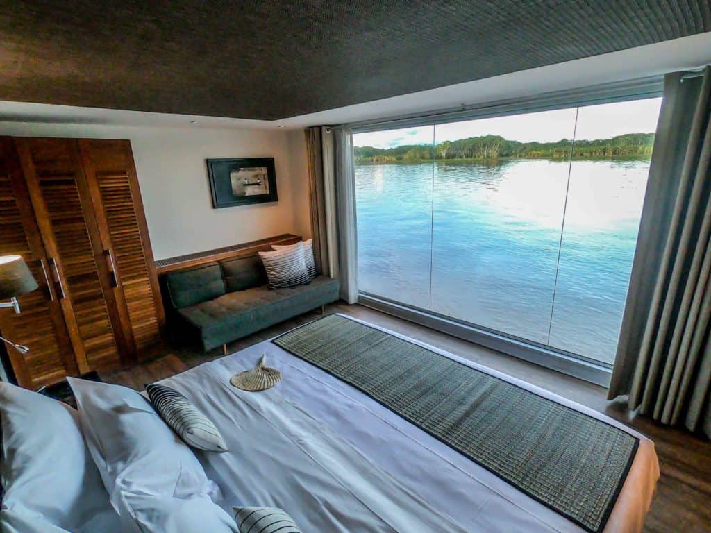 A cabin aboard the Aria with floor to ceiling windows, couch, closet and king sized bed.