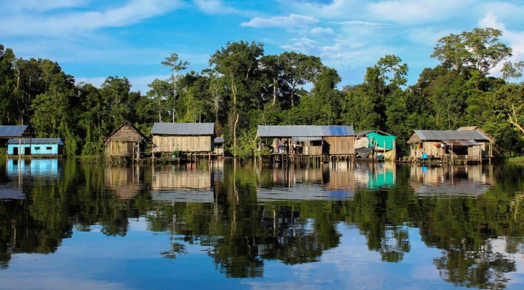 A village in the Amazon on stilts with the jungle behind.