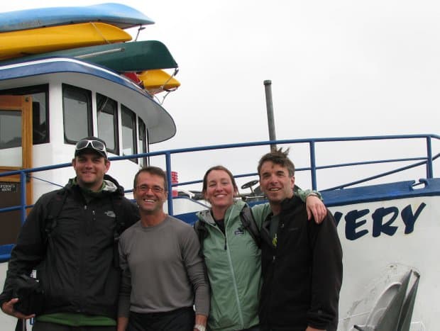 A group of people standing at the bow of the small ship Discovery. 