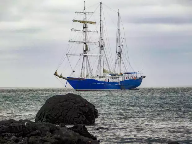 The small ship sailing ship S/S Mary Anne anchored in the ocean off the Galapagos Islands.
