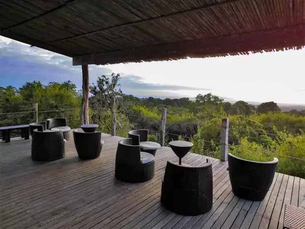 Thatched roof and deck with tables and chairs overlooking the landscape at the Galapagos Safari Camp.