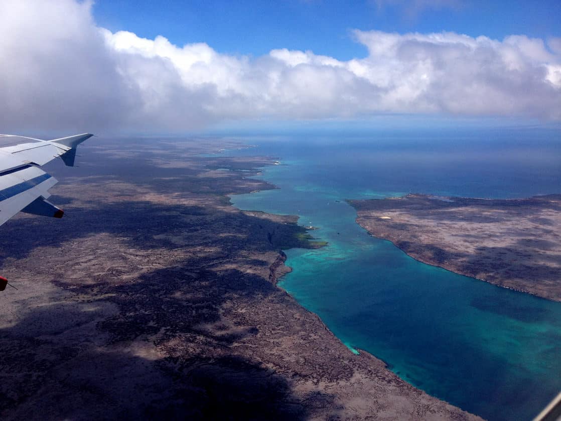 Aerial view of the emerald green ocean and volcanic rock island.