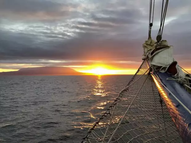 Tip of the narrow bow with net sailing on the ocean with the sunset.
