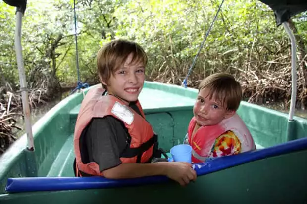 Children on an excursion from their small ship cruise getting up close to the forest on a skiff. 