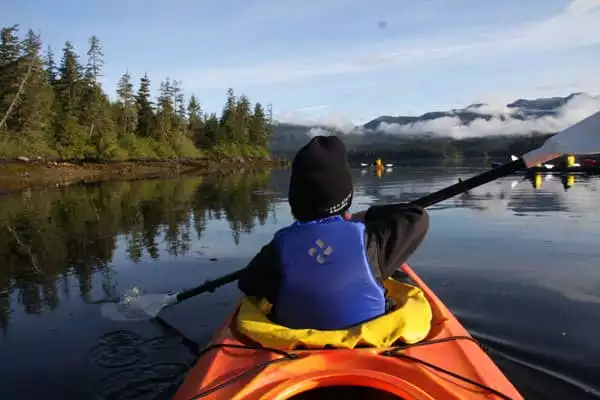 Guest from a small ship cruise kayaking in calm waters in Alaska. 