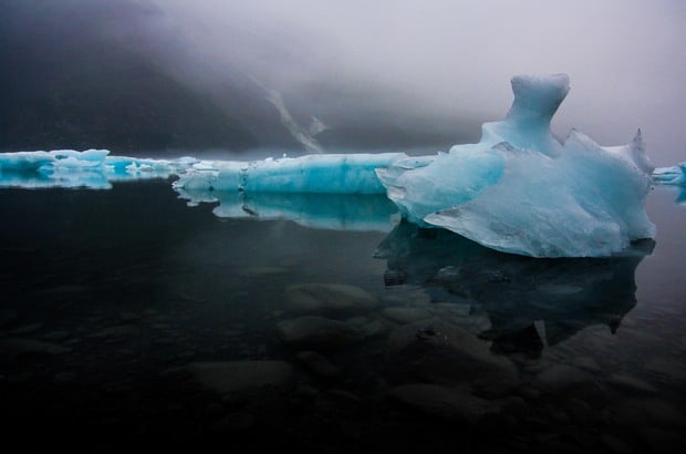 Bright blue glaciers in a dark misty bay at Kenai Fjords Alaska. 