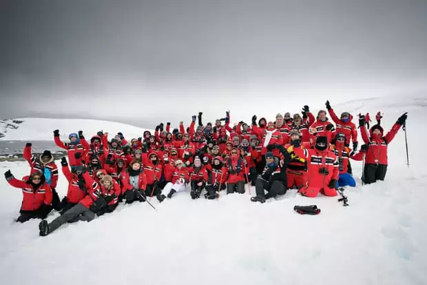 Group from a small cruise ship in Antarctica wearing their red polar expedition parkas on the snow. 