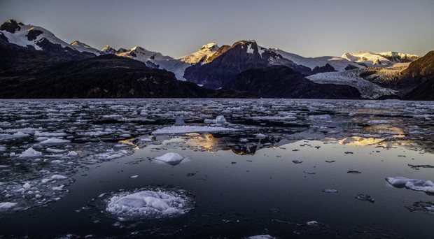 Floating ice below snow covered mountains in Patagonia. 
