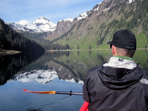 A man kayaking on still water in Alaska. 