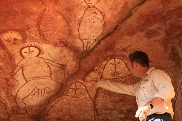 An Australian guide pointing at artwork inside of a cave in the Kimberley