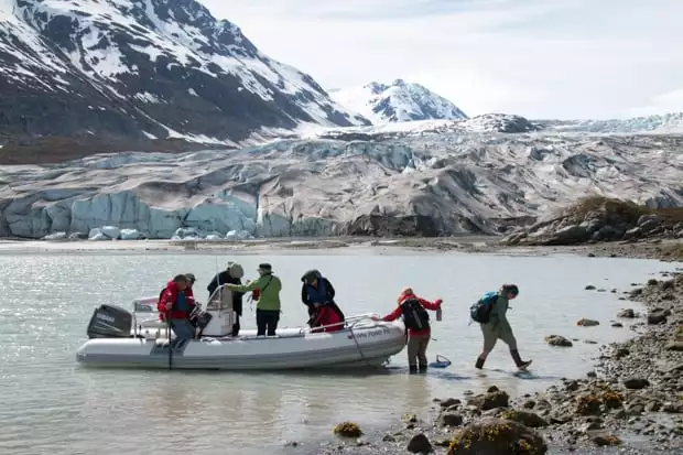Guests on a skiff excursion from their small ship to the shore in Alaska to walk by the glacier. 