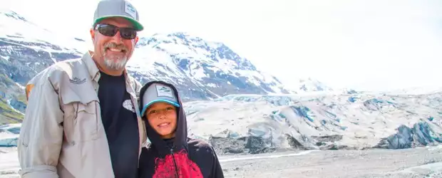 Founder Todd Smith and son posing in front of a glacier from their small ship cruise to Alaska. 