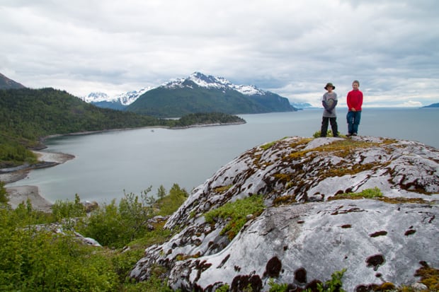 Two children posing on a rock overlooking a bay in Alaska.