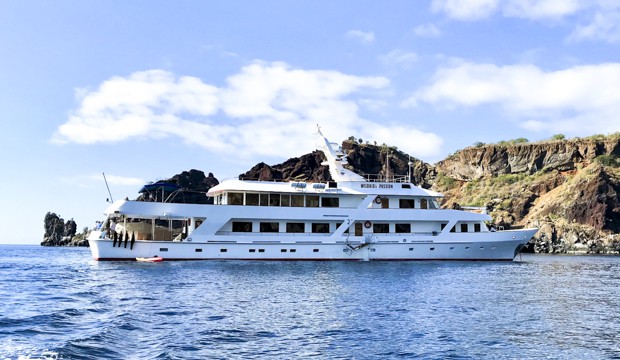 Motor yacht WildAid's Passion small ship cruise anchored next to the shoreline of the Galapagos.