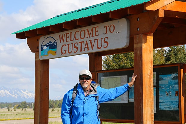 Adventuresmith founder Todd Smith standing in front of Welcome to Gustavus sign in Alaska.