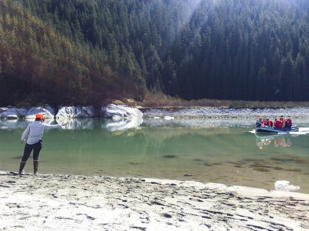 Guide on shore guiding in the next group of guests on a skiff from their small ship in ALaska. 