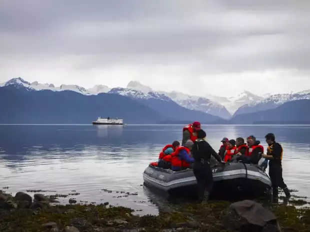 Guests entering their skiff from shore to go back to their small ship cruise in Alaska. 