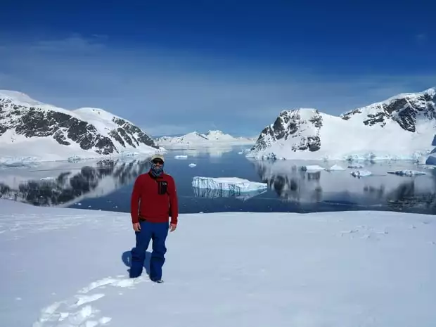 Guest from small ship smiling in front of icebergs at Danco Island Antarctica. 