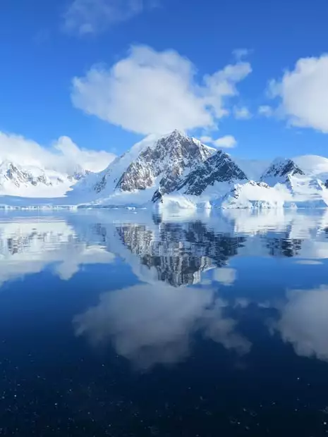 View of mountain reflections at Wilhelmina Bay from a small ship in Antarctica.