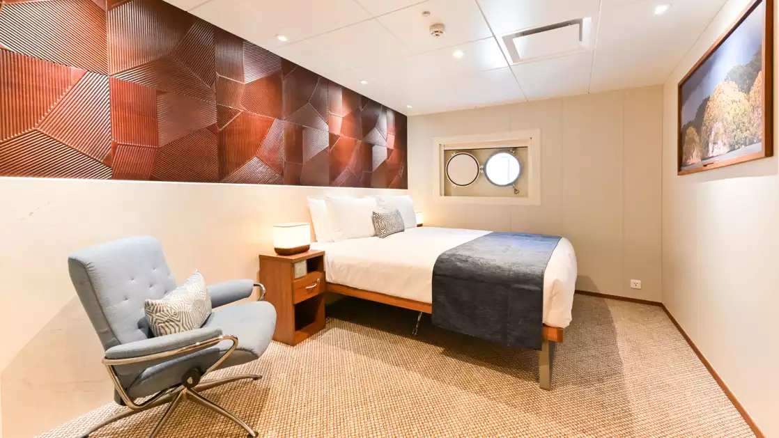 a large comfortable bed also featuring an authentic olf style porthole aboard the Coral Geographer off the coast of Australia
