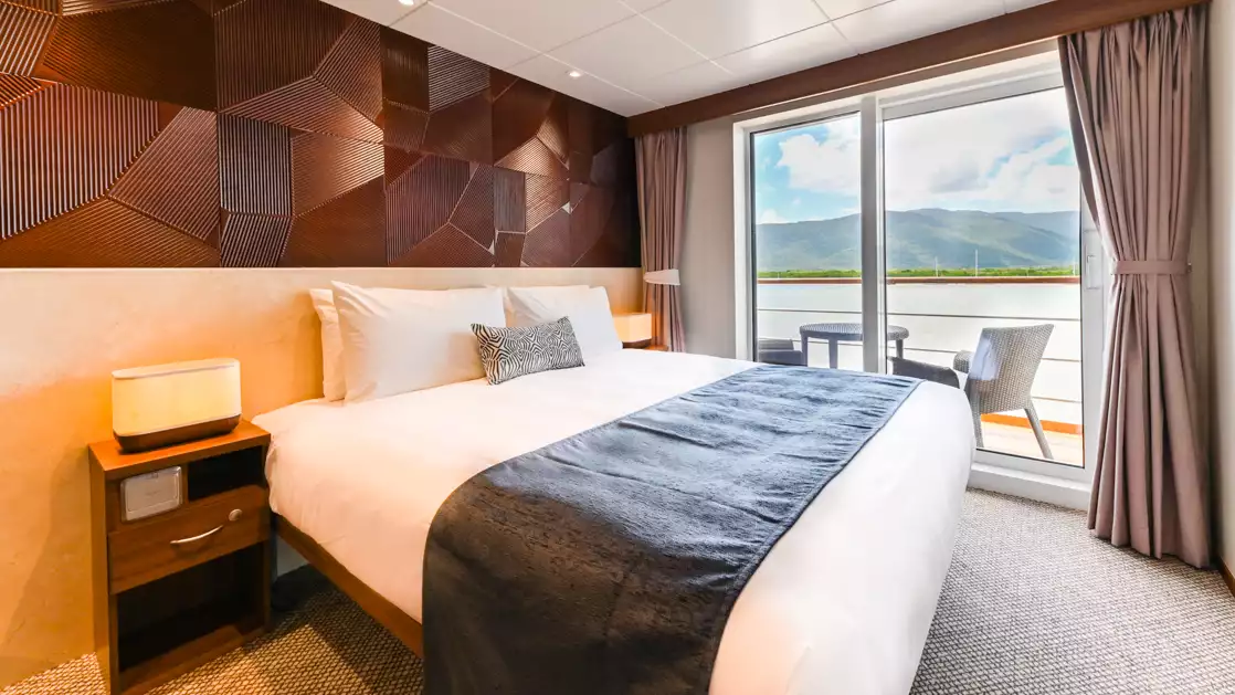 A large comfortable bed close enough to your balcony that you can watch aboard the Coral Geographer off the coast of Australia